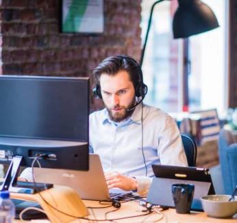 Man in deep concentration in a non-office setting with a monitor, laptop and table up in front of him